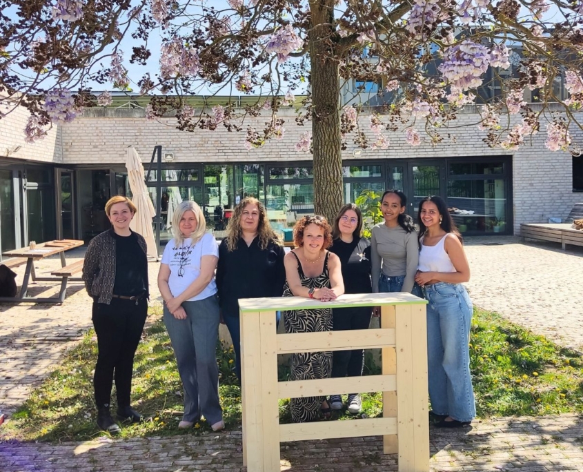 Team steht lachend hinter selbstgebautem Tresen im Schreiner-Workshop