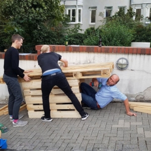 Mitarbeiter bauen gemeinsam Palettenmöbel beim Teambuilding-Event